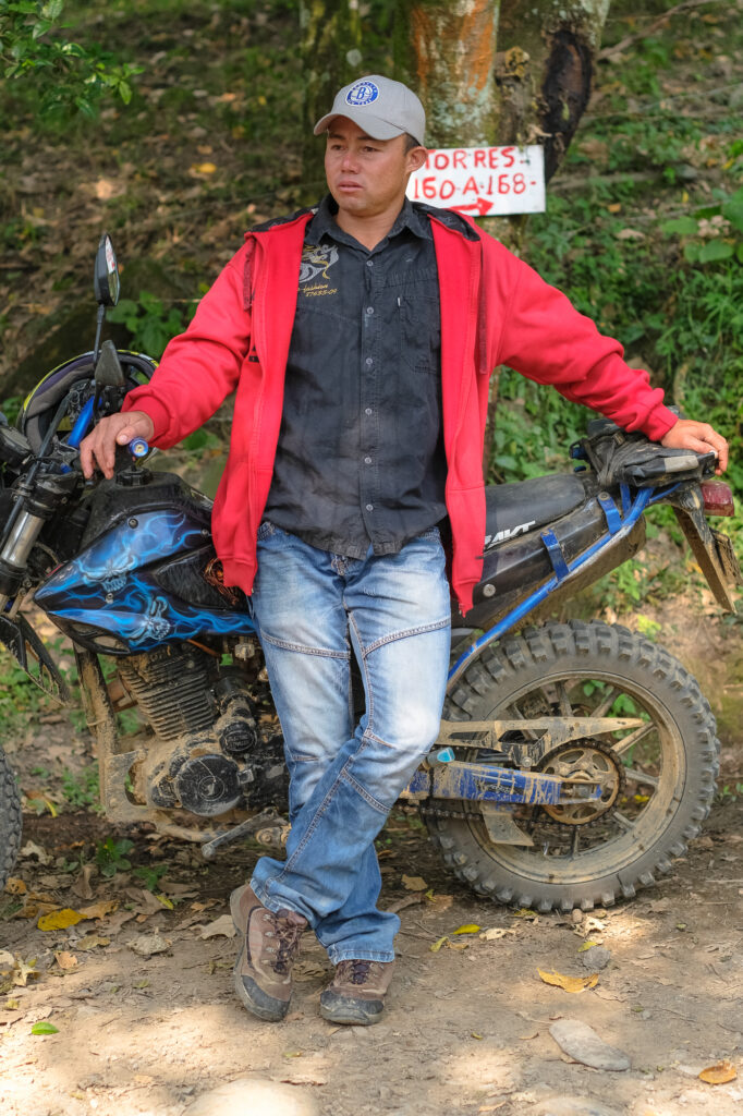 Photo of Mr. Gonzalo Cifuentes, in baseball cap and red jacket, leaning against motorbike