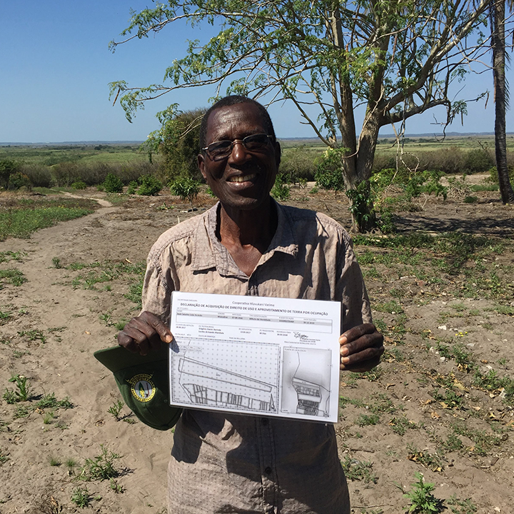 Tanzanian man in field holding up an evaluation chart