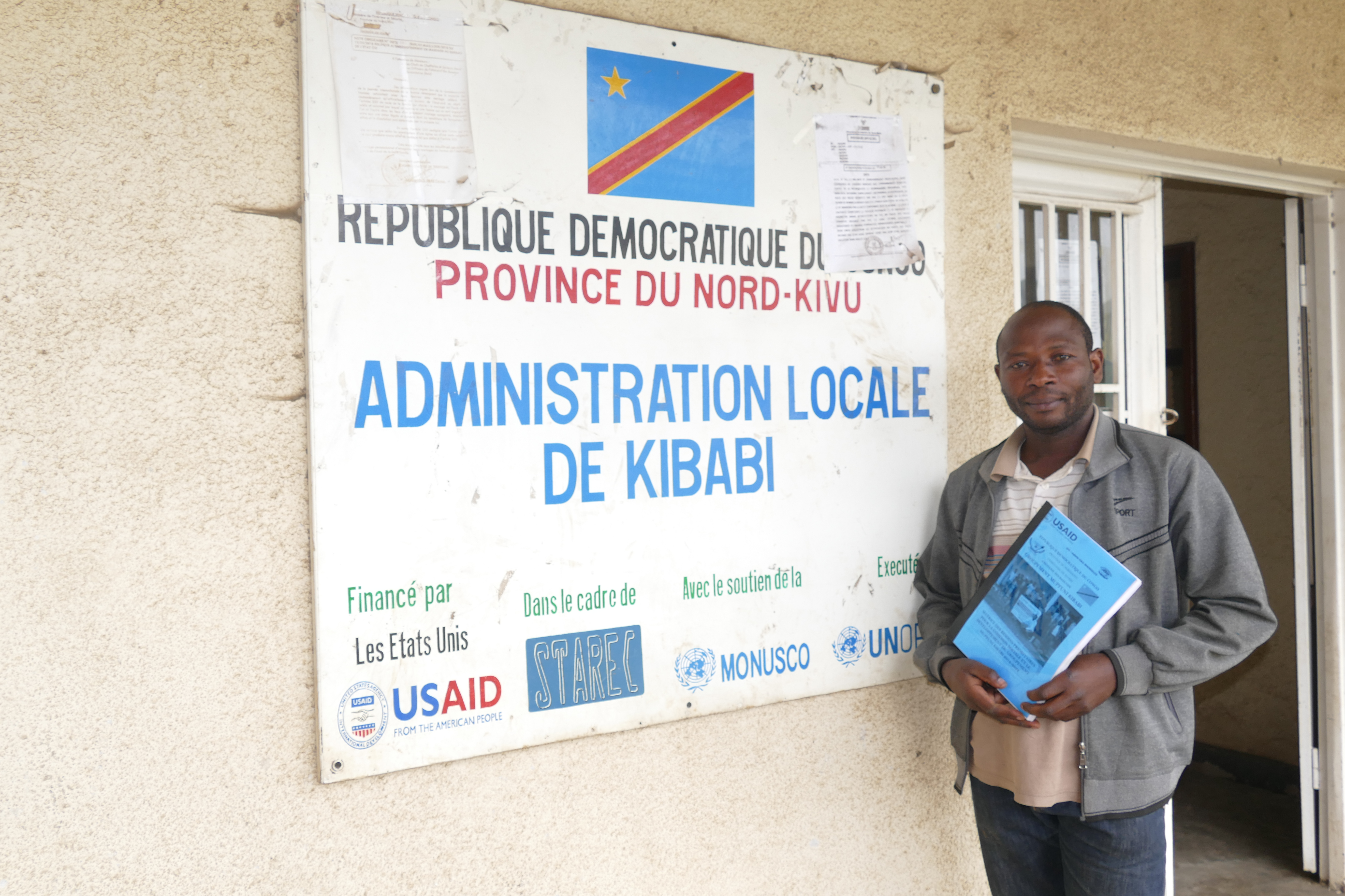 Man holds USAID manual in front of USAID banner